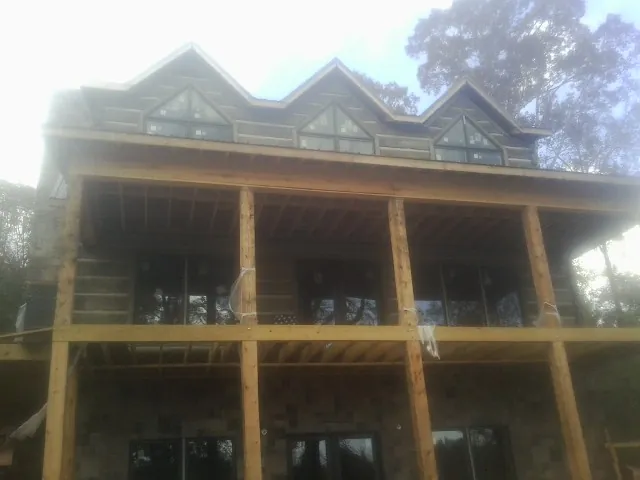 Dormers and porch framing on a large log home under construction — Roof Coating work by our crew in West Grove