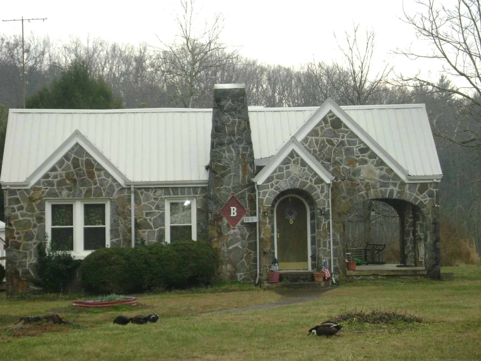 White metal roof on a stone cottage with steep gables in West Grove