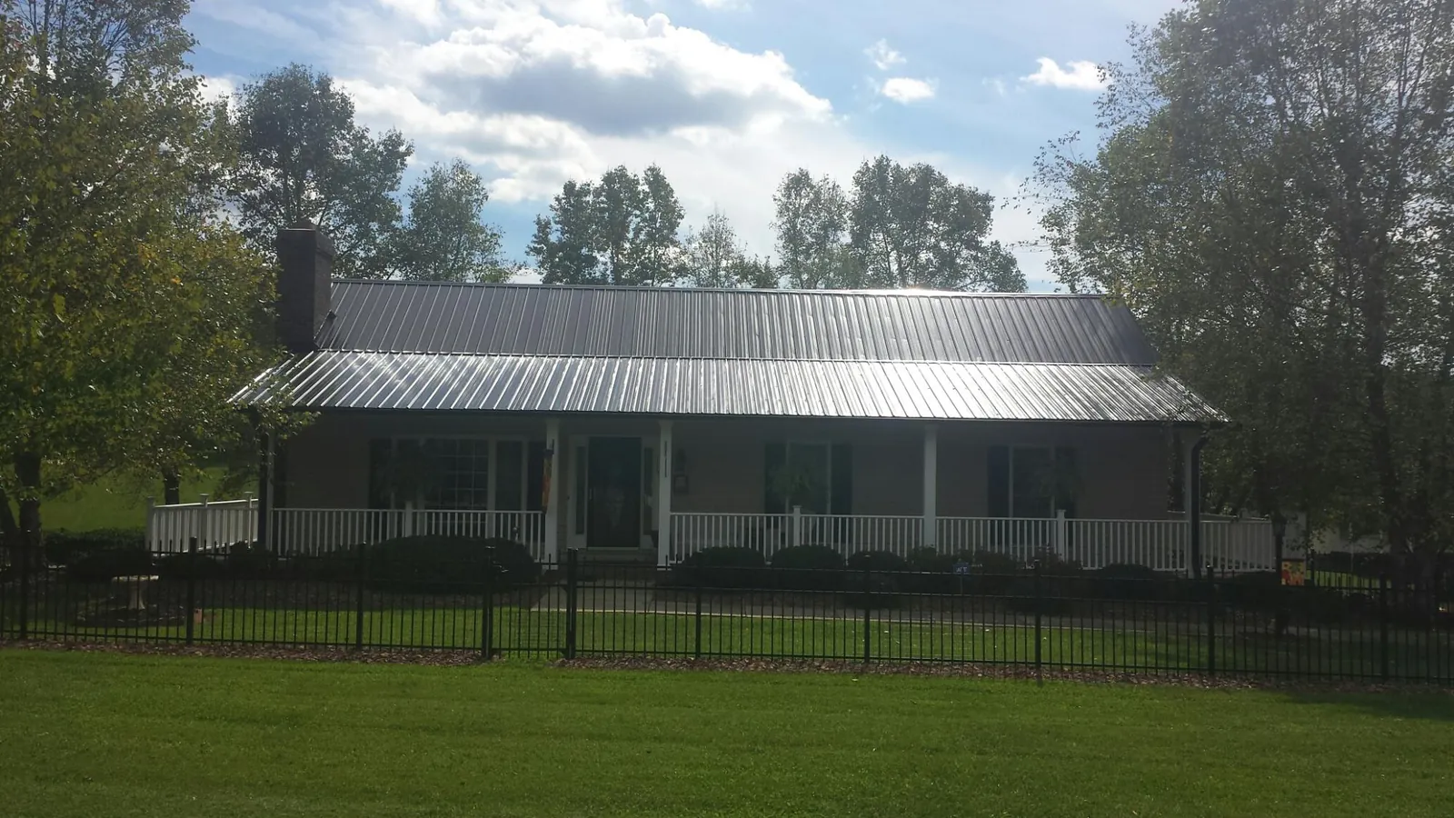 Gray metal roof on a brick ranch with a full width front porch — Gutter Guard Installation work by our crew in West Grove