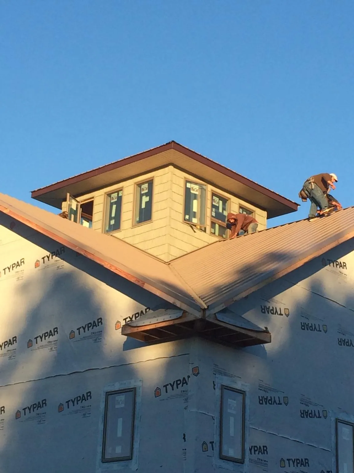 Roofers working around a rooftop cupola on a new metal roof at sunset — Roof Waterproofing in West Grove by Roofing Brothers